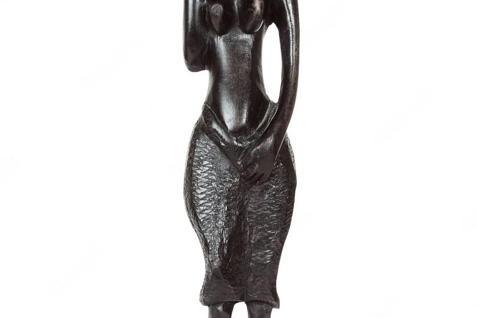 An African antique black ebony statue of woman carrying a water jug on her shoulder, a skirt that looks almost like fish scales and naked breasts against a white background