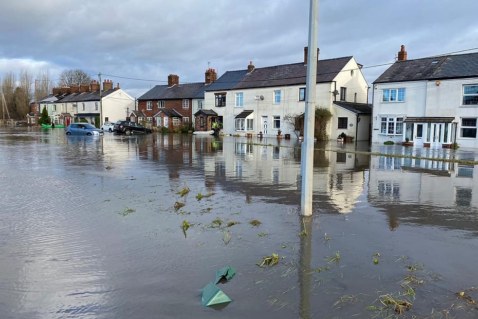 Flooded UK town; all the houses have water across their front gardens and coming into the front doors. There's a car or two also submerged.